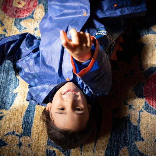 A child lying on the ground pointing up